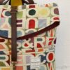 Detalle de mochila reciclada de tapicería vintage con letras y colores