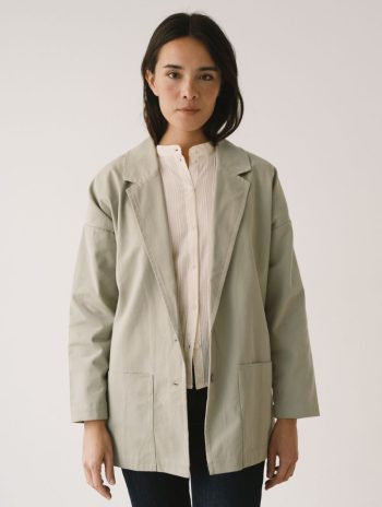 Una modelo con una americana de sarga de algodón orgánico en verde salvia y corte relajado, vista de frente.