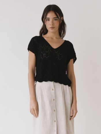 Mujer con un top calado negro de tricot de algodón orgánico con escote en pico y manga corta