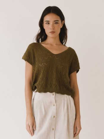Mujer con top de punto calado en verde oliva, escote en V y manga corta, combinado con falda larga de lino beige